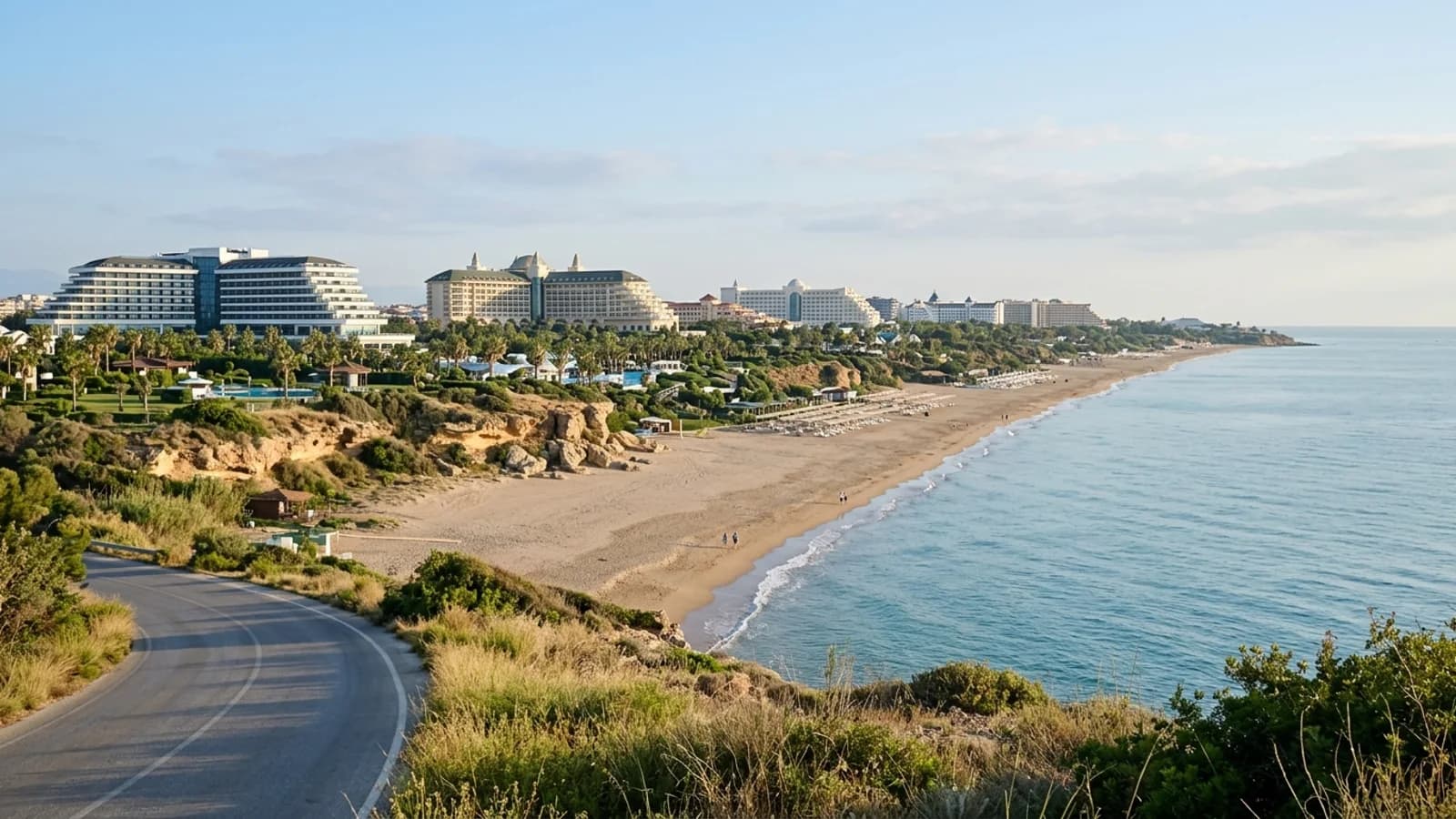 Zandstrand in Lara met lage zandsteenkliffen en grote resorthotels die in tuinen liggen.